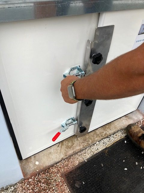 Main enclenchant un poussoir au centre du batardeau pour comprimer les joints