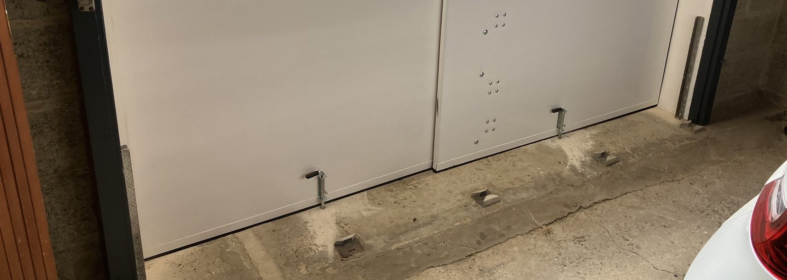 Batardeaux grande largeur installés derrière une porte de garage, poussoirs enclenchés