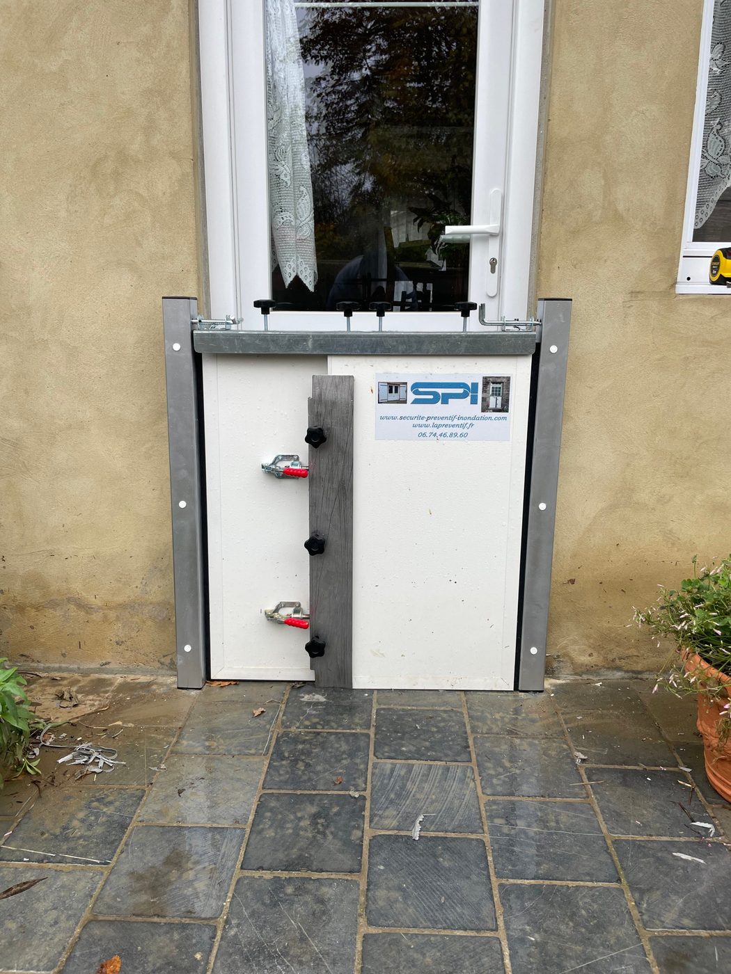 Batardeau SPI installé sur une porte-fenêtre d'habitation, entre deux cornières murales